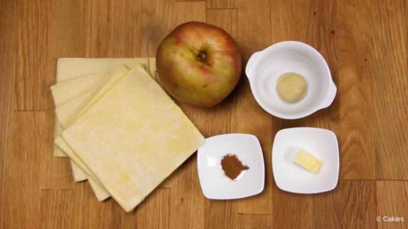 Ingrediënten voor appelbeignets met bladerdeeg op een houten ondergrond.